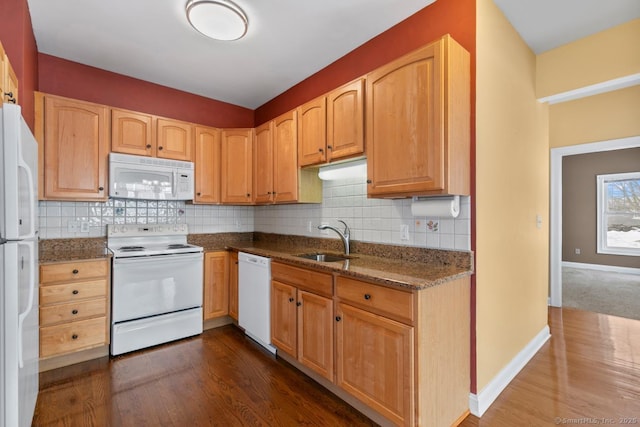 kitchen with white appliances, a sink, baseboards, decorative backsplash, and dark stone countertops