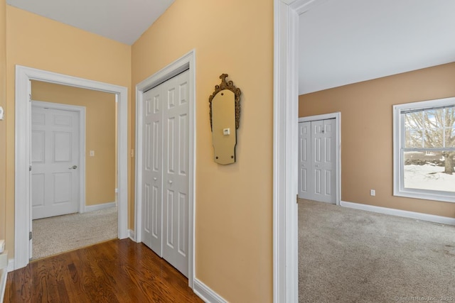 hall with dark colored carpet and baseboards