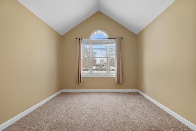 empty room featuring carpet floors, baseboards, and vaulted ceiling