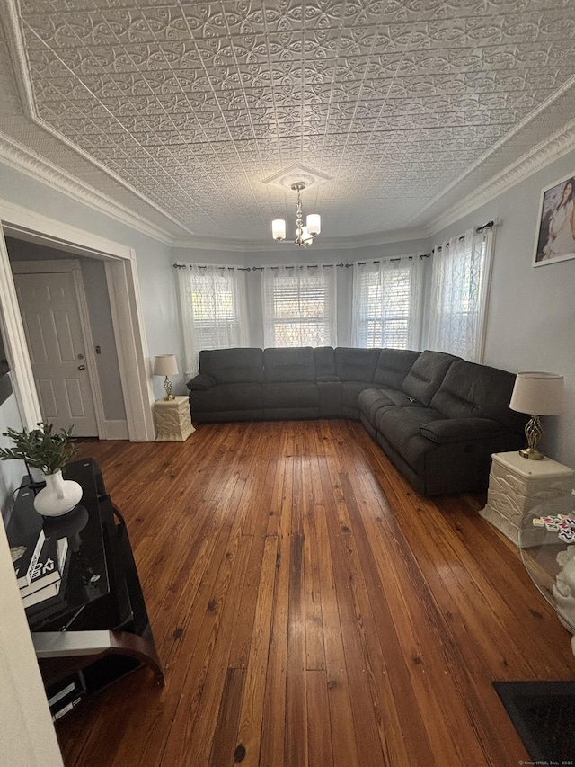 living room with ornamental molding, wood finished floors, an ornate ceiling, and an inviting chandelier