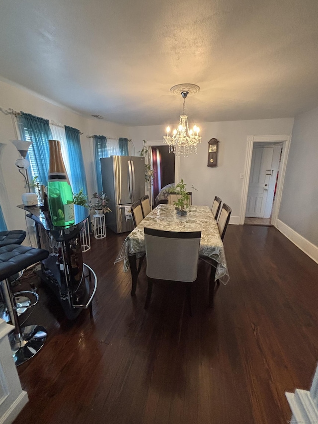 dining space featuring a chandelier, dark wood finished floors, a textured ceiling, and baseboards