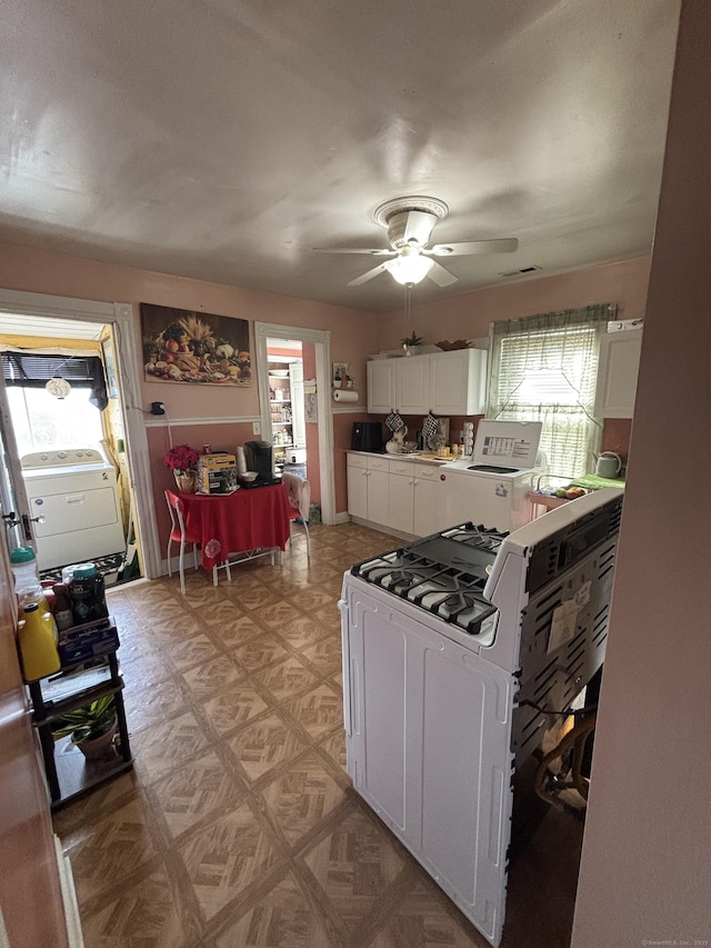 kitchen featuring light floors, plenty of natural light, white cabinetry, and white range with gas stovetop