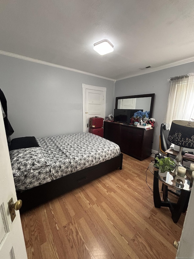 bedroom featuring crown molding, visible vents, and light wood-style floors