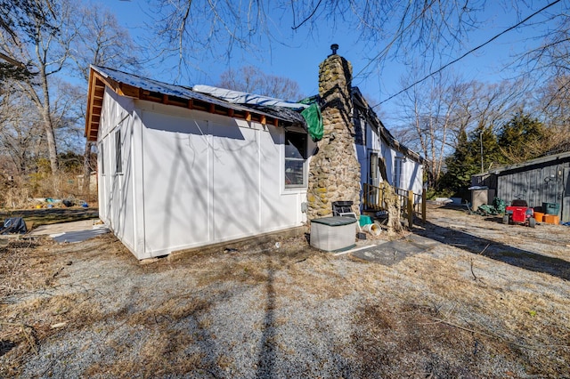 view of side of property featuring metal roof and a chimney