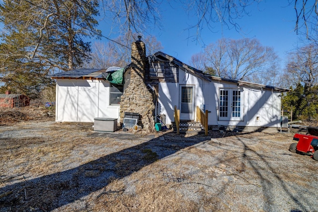 back of house with entry steps and a chimney