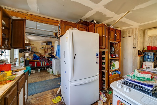 kitchen featuring wooden walls, wood finished floors, light countertops, range, and freestanding refrigerator