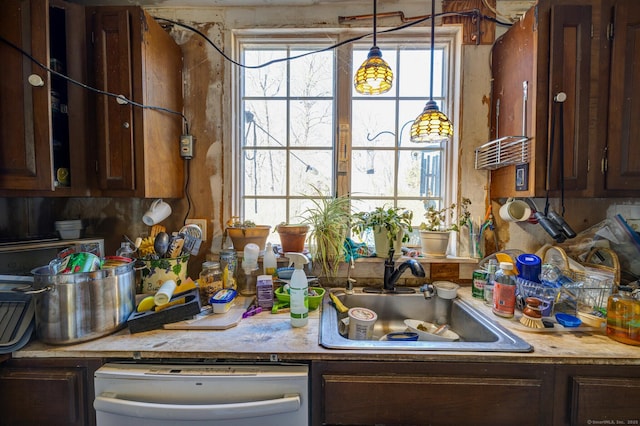 kitchen with light countertops, a sink, and dishwashing machine