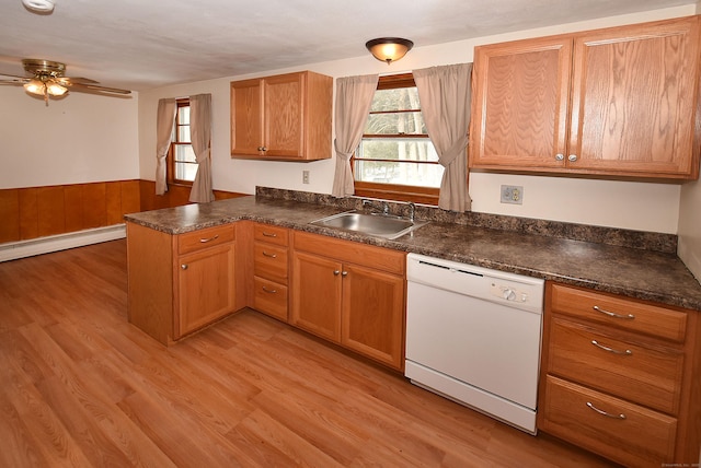 kitchen featuring a peninsula, dark countertops, white dishwasher, and a sink