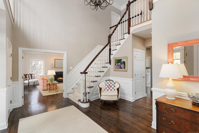 entryway with dark wood-style floors, a wainscoted wall, crown molding, and stairs