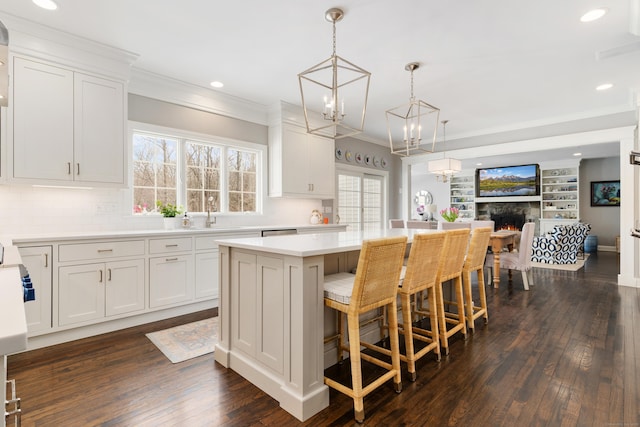 kitchen featuring a breakfast bar area, a kitchen island, white cabinetry, light countertops, and pendant lighting