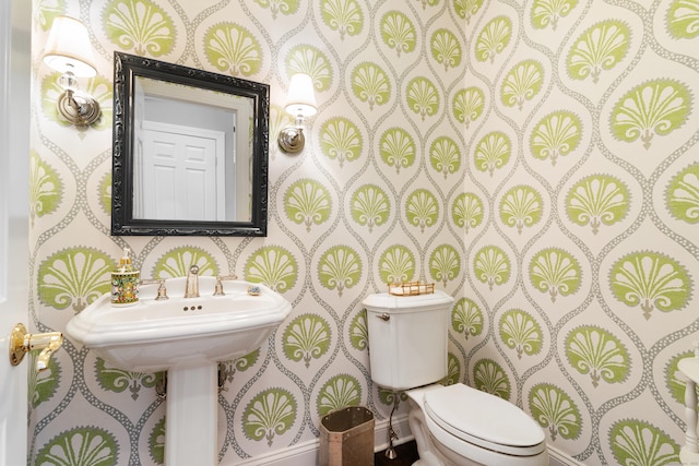 half bathroom with toilet and wallpapered walls