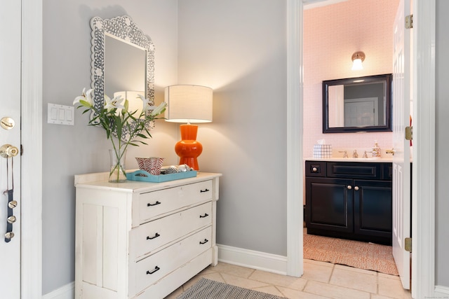 interior space featuring light tile patterned floors, baseboards, and a sink