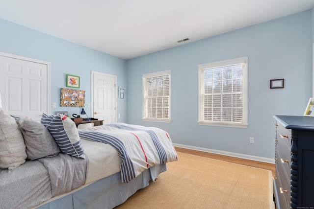 bedroom with light wood-type flooring, baseboards, and visible vents