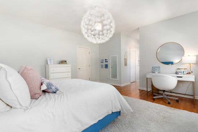 bedroom with an inviting chandelier, baseboards, and wood finished floors