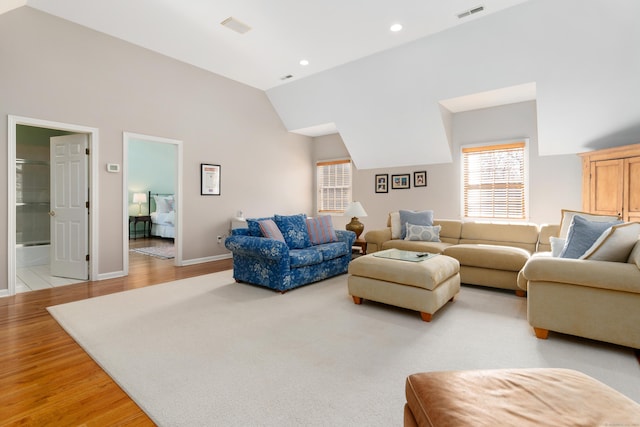 living area with lofted ceiling, recessed lighting, visible vents, light wood-style flooring, and baseboards