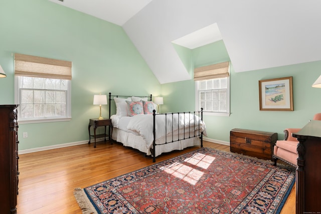 bedroom with lofted ceiling, light wood-type flooring, and baseboards