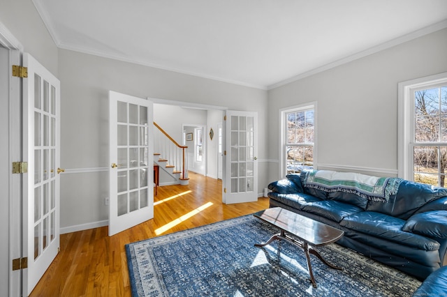 living room with plenty of natural light, crown molding, wood finished floors, and french doors