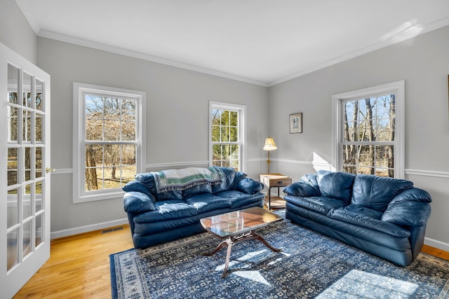 living room featuring ornamental molding, visible vents, baseboards, and wood finished floors