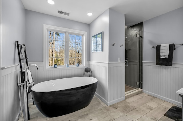 full bathroom with wainscoting and a shower stall