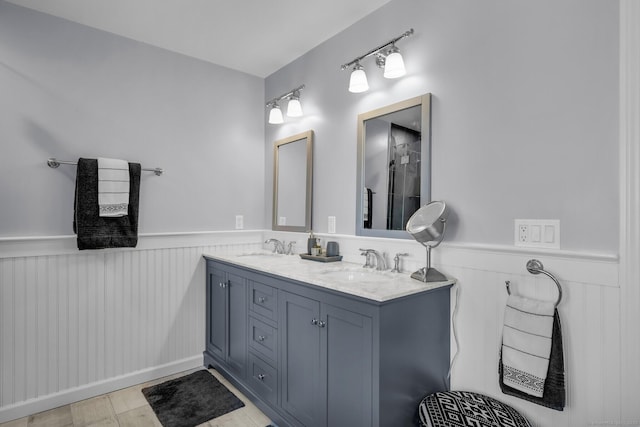 full bath featuring double vanity, wainscoting, and a sink