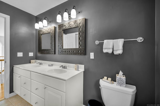 full bath featuring toilet, double vanity, a sink, and tile patterned floors