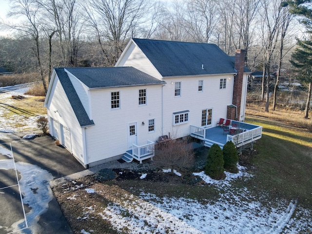 exterior space with a garage, roof with shingles, a chimney, and a wooden deck