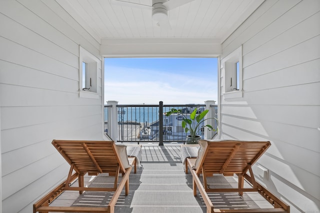 balcony featuring a water view and ceiling fan