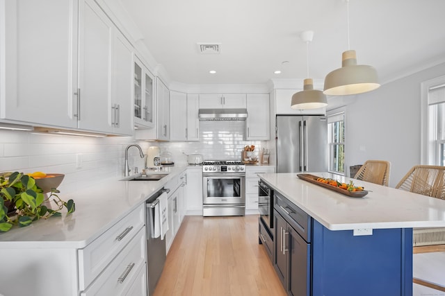 kitchen featuring a kitchen breakfast bar, decorative light fixtures, stainless steel appliances, white cabinetry, and a sink