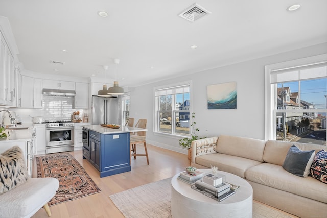 living area with baseboards, light wood finished floors, visible vents, and recessed lighting