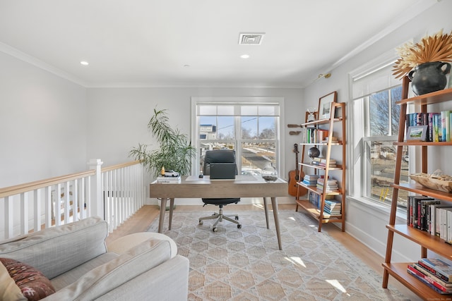 office with ornamental molding, light wood-type flooring, visible vents, and a healthy amount of sunlight