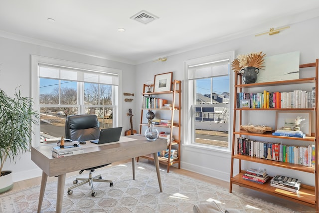 office area with ornamental molding, light wood finished floors, visible vents, and baseboards