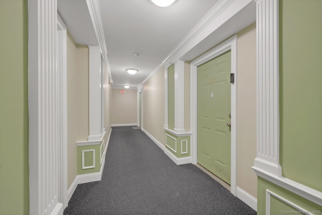 hall featuring baseboards, dark colored carpet, ornamental molding, and ornate columns