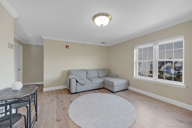 living area with ornamental molding, baseboards, visible vents, and light wood finished floors