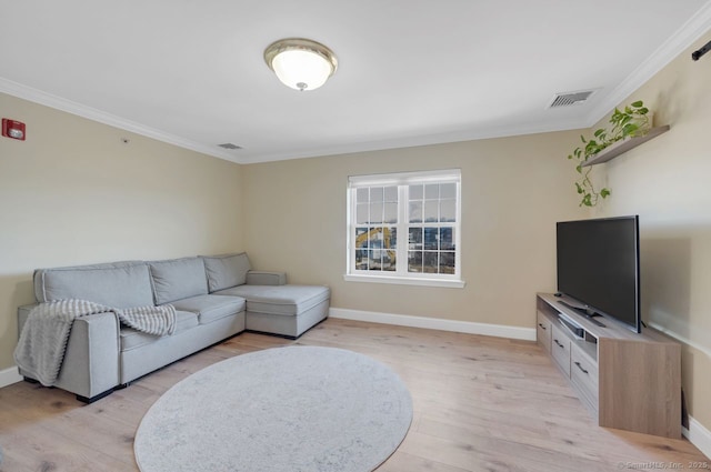 living room featuring ornamental molding, light wood finished floors, visible vents, and baseboards