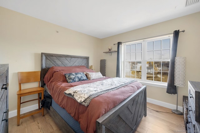 bedroom with light wood finished floors, visible vents, and baseboards