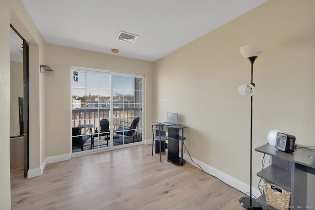 office space with light wood-style floors, baseboards, and visible vents