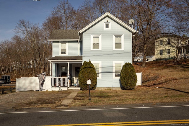 traditional-style home featuring covered porch and a shingled roof