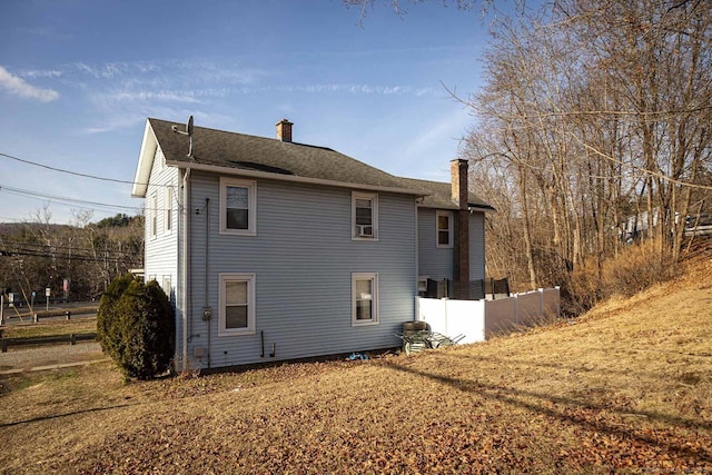 back of property with a shingled roof and a chimney