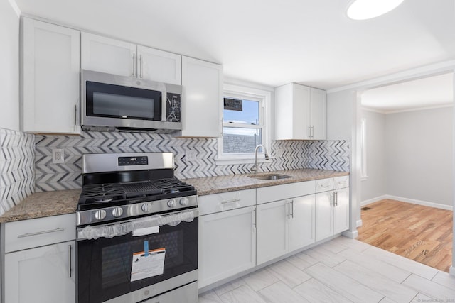 kitchen featuring light stone counters, tasteful backsplash, appliances with stainless steel finishes, white cabinetry, and a sink