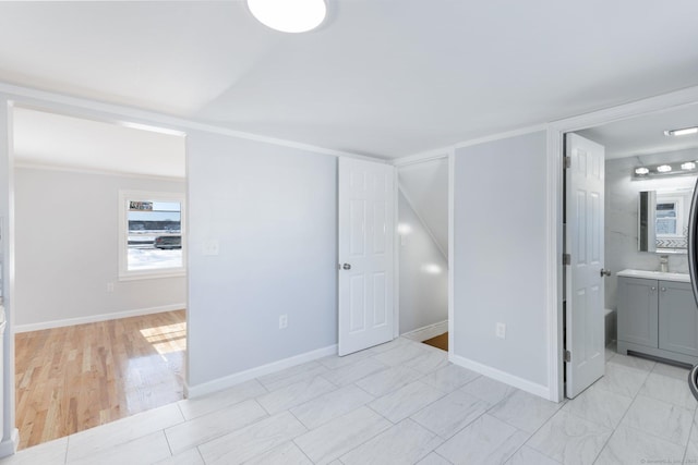 unfurnished bedroom featuring ensuite bath and baseboards