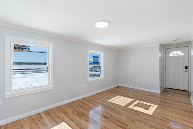 entryway featuring ornamental molding, light wood-type flooring, and baseboards