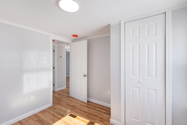 unfurnished bedroom with a closet, light wood-style flooring, and baseboards