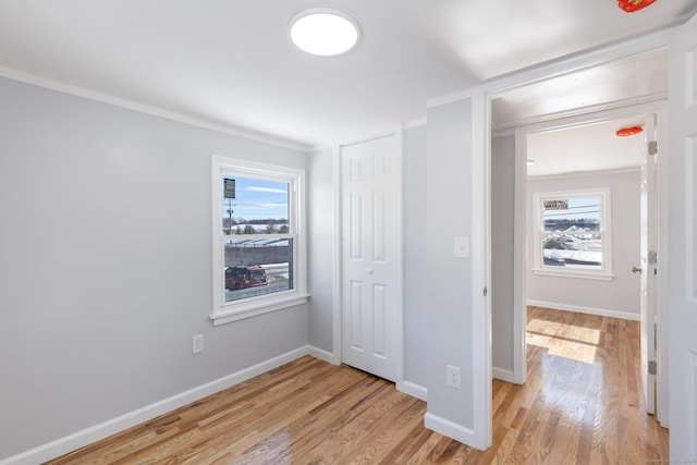 unfurnished bedroom featuring light wood-type flooring, multiple windows, and baseboards