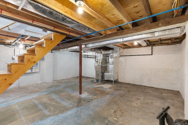 unfinished basement featuring stairway and heating unit