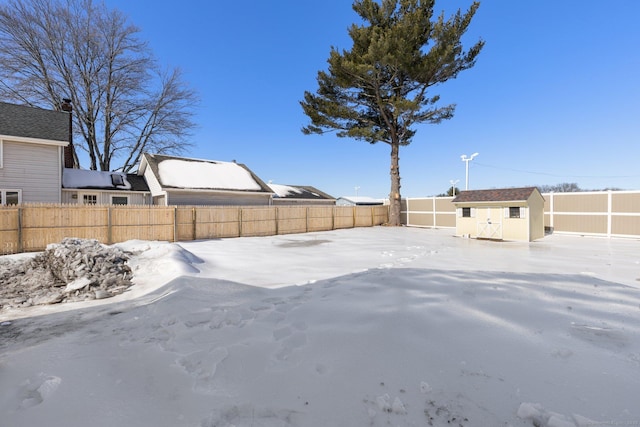 yard covered in snow with a shed, an outdoor structure, and a fenced backyard