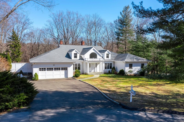 view of front facade with a chimney, aphalt driveway, an attached garage, fence, and a front yard