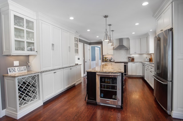 kitchen with stainless steel appliances, wine cooler, white cabinets, and wall chimney range hood