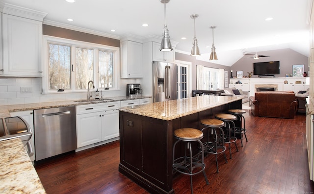 kitchen with ceiling fan, a kitchen breakfast bar, stainless steel appliances, white cabinetry, and a sink