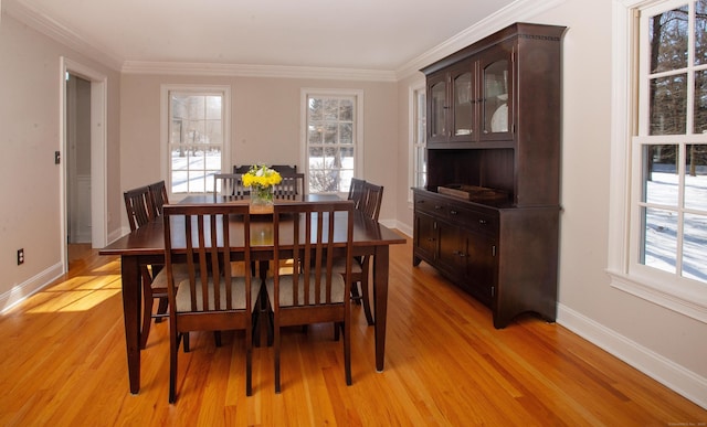 dining space with crown molding, plenty of natural light, baseboards, and light wood-type flooring