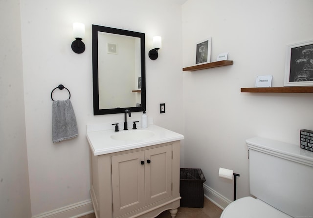 half bath with vanity, toilet, baseboards, and visible vents